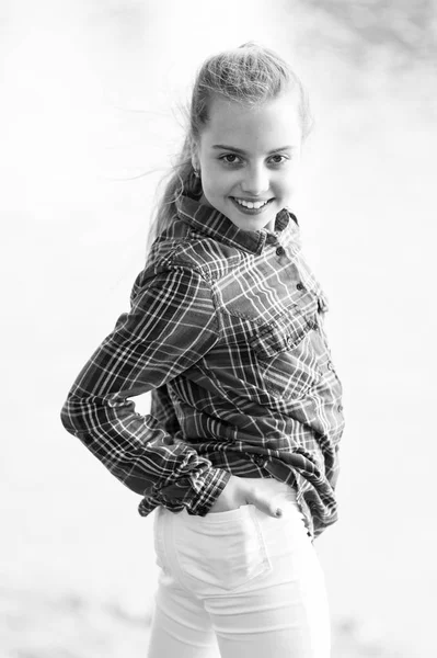 Una niña. Adorable bebé con el pelo largo y rubio sonriendo en estilo casual a cuadros al aire libre. Feliz bebé vistiendo ropa de verano de moda. Bebé pequeño con linda sonrisa en el paisaje natural —  Fotos de Stock