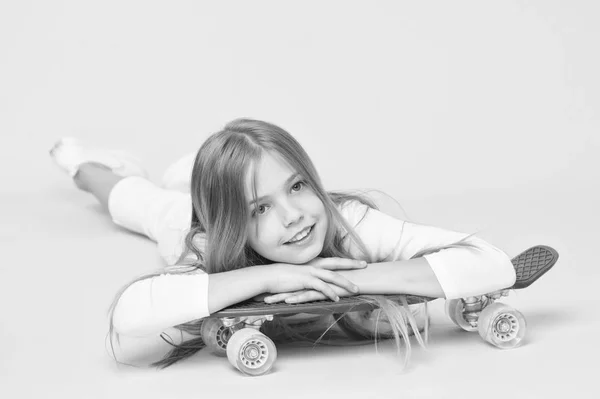 トレンディな女の子。女の子はスケートボードに乗るのが好きです。アクティブなライフスタイル。ペニーボードピンクの背景を楽しんでいる女の子。子供愛らしい子供の長い髪はペニーボードに乗って崇拝。ペニーボードに乗って、トリックを行う — ストック写真