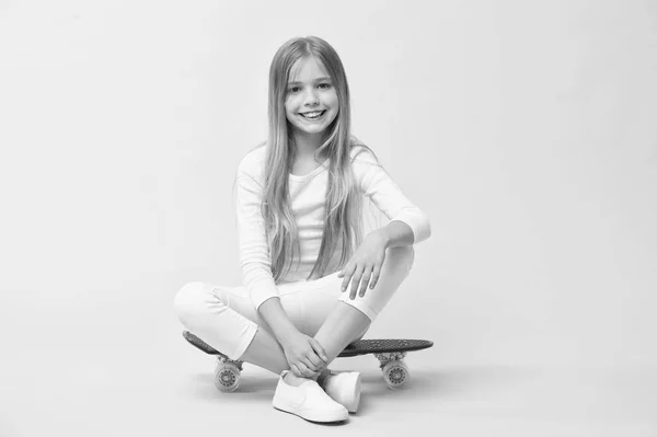 Rida Penny Board och göra tricks. Tjejen gillar att rida skateboard. Aktiv livsstil. Flicka ha kul med Penny Board rosa bakgrund. Kid bedårande barn långt hår Adore rida Penny Board. Lycklig barndom — Stockfoto