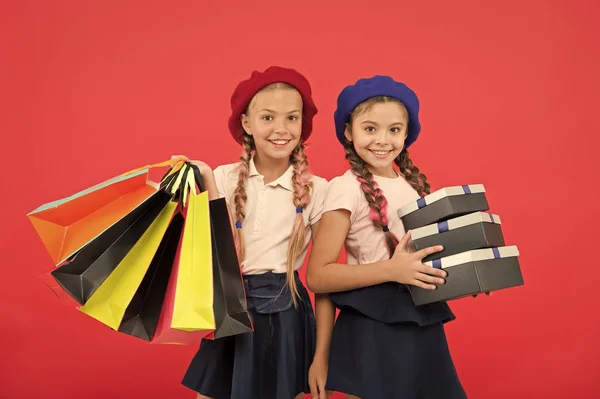 ショッピング モールの服と取りつかれています。買い物中毒の概念。最高の友人と楽しみになるショッピングします。子供かわいい女子中学生は、束の買い物袋を保持します。子供の赤い背景のショッピングで満足 — ストック写真