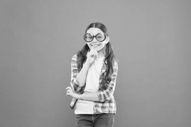 Mutlu ve şık. Turuncu arka planda güneş gözlüğü takan mutlu çocuk. Küçük kız renk filtresi ile fantezi gözlük gülümseyerek mutlu. Küçük model mutlu bir görünüm