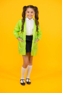 Su geçirmez aksesuarlar yağmurlu sonbahar günü neşeli ve keyifli olun. Yeşil pelerinli kız öğrenci. Su geçirmez aksesuar. Çocuk kız mutlu su geçirmez pelerin giymek. Uygun giysilerle sonbahar havalarının keyfini çıkarın