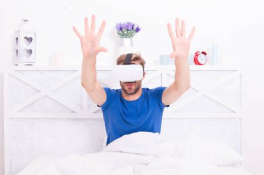 En iyi sanal gerçeklik deneyimi. Yatakta VR kulaklık takan yakışıklı adam. Beyaz adam yatak odasında sanal gerçeklik gözlüğü kullanıyor. VR içerisindeki etkileyici canlandırma