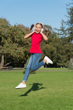 Hiç bitmeyen neşe. Kız müzik modern gadget dinleme. Çocuk kablosuz kulaklık dans atlama ile mutlu. Stereo kulaklıklar. Modern teknolojiyi kullanan bir çocuk. Modern çocuk. Mükemmel yüksek ses