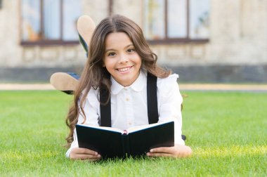 Temel eğitim. Ders dışı okumalar. Dışarıda kitap okuyan şirin küçük bir çocuk. Sevimli küçük kız okumayı öğreniyor. Okul üniforması en sevdiği kitapla çimlerin üzerinde yatıyor. Konsept öğrenimi