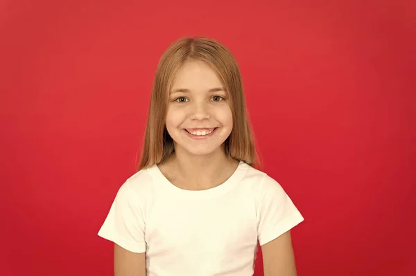 Emoções sinceras. Conceito de sorriso brilhante. Menina feliz rosto sorridente sobre fundo vermelho. Criança emocional alegre rosto sorridente. Menina adorável alegre sorrindo. Positivo e otimista. Humor alegre — Fotografia de Stock