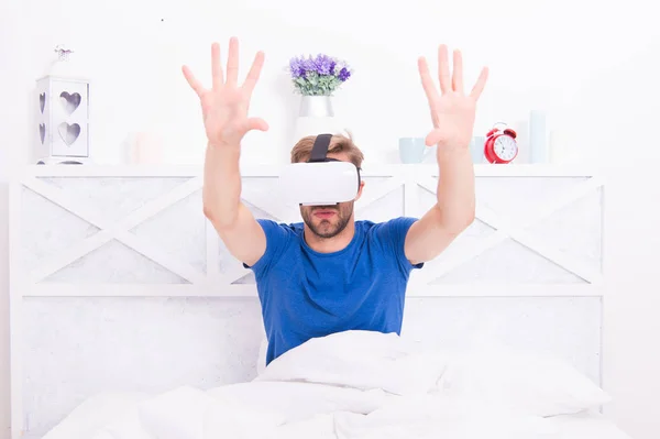 La migliore esperienza VR. Un bel ragazzo con le cuffie VR a letto. Uomo caucasico che usa occhiali VR in camera da letto. Rendering immersivo in VR — Foto Stock