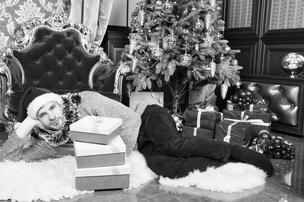 Tradiciones navideñas. El hombre celebra el año nuevo o la fiesta de Navidad. Hombre sombrero de santa celebrar la Navidad barroco interior abeto decorado y regalos. concepto de regalos de Santa Claus y Navidad — Foto de Stock