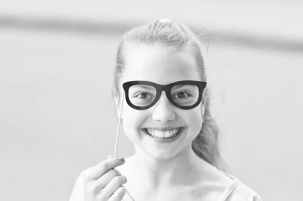 Geef elk kind een gelukkige kindertijd. Schattig klein kind met gelukkige glimlach en grappige blik door glazen rekwisieten. Gelukkig klein meisje met grote glimlach op de zomerdag. Happy International Childrens dag — Stockfoto