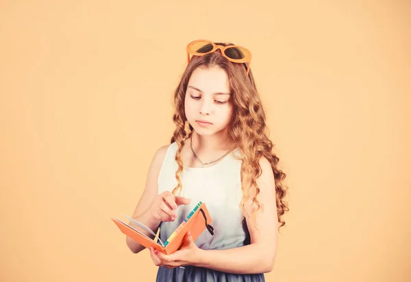 Pequeña chica feliz en gafas con cuaderno. Pequeña chica de belleza escribir sus recuerdos. notas del diario. libro de lectura. Moda de verano. hacer planes para vacaciones de verano y vacaciones. estudiante leer libro — Foto de Stock