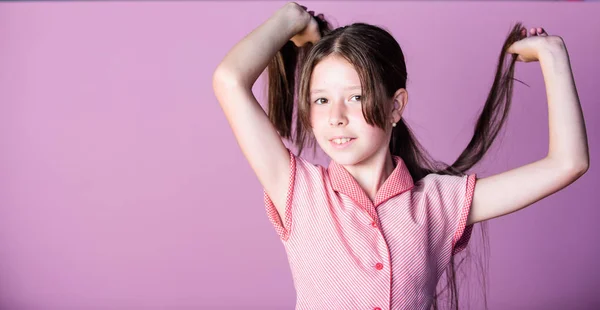 Dicas de beleza para cabelos arrumados. Conceito de inocência. Feliz dia das crianças. Beleza pura. Menina longo cabelo brilhante saudável fechar. Menina com cabelo comprido. Criança bonito rosto com cabelo adorável no fundo rosa — Fotografia de Stock