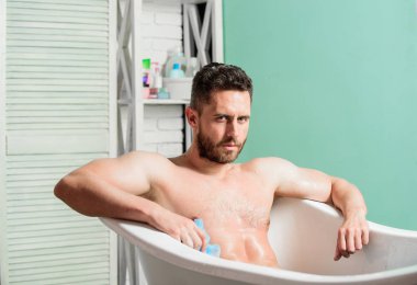 adam köpük sünger ile kaslı vücut yıkama. Küvette maço çıplak. Maço çekici çıplak adam. Banyodaki seksi adam. Köpükleri suyla dikkatlice yıkayın. Seks ve rahatlama konsepti. tutku ve şehvet