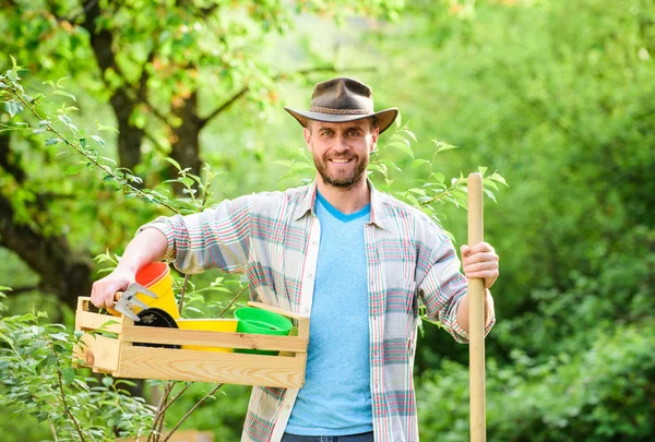 Feliz Dia da Terra. Eco vida. agricultura e cultivo agrícola. Equipamento de jardim. Eco fazenda. Colheita. Homem do rancho musculado de chapéu de cowboy. agricultor sexy segurar pá e caixa com pote. Flores de estufa — Fotografia de Stock