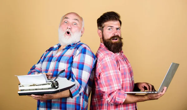 retro typewriter vs laptop. New technology generation. technology battle. Modern life. youth vs old age. business approach. two bearded men. Vintage typewriter. father and son. Master new technology