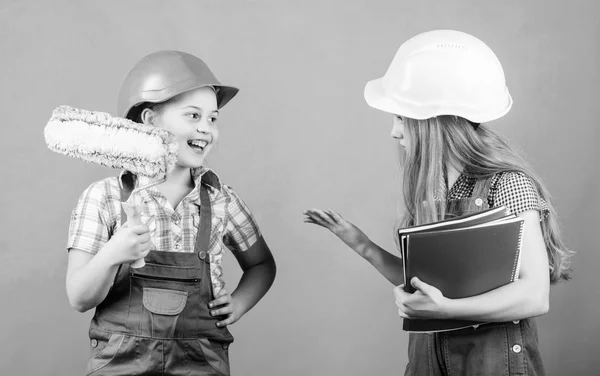 Herramienta de rodillos. Niños pequeños en casco con tableta y rodillo. Día del Trabajo. 1 de mayo. Inspector Foreman. Reparar. niñas pequeñas que reparan juntos en el taller con rodillo. proyecto escolar. usando rodillo en casa —  Fotos de Stock