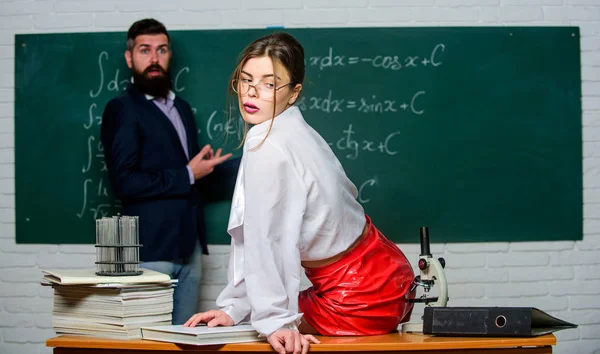 与同事调情。科学是性感的。性感的女孩坐在桌子上，而男人站在黑板。每个人都梦想着这样的老师。皮裙的迷人老师。可爱的老师。傲慢的学生 — 图库照片