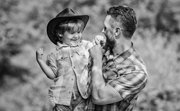 Niño y padre en el fondo de la naturaleza. Espíritu de aventuras. Fuerte como padre. Poder siendo padre. Niño divirtiéndose papá vaquero. Familia rústica. Creciendo lindo vaquero. Ayudante pequeño en el jardín — Foto de Stock