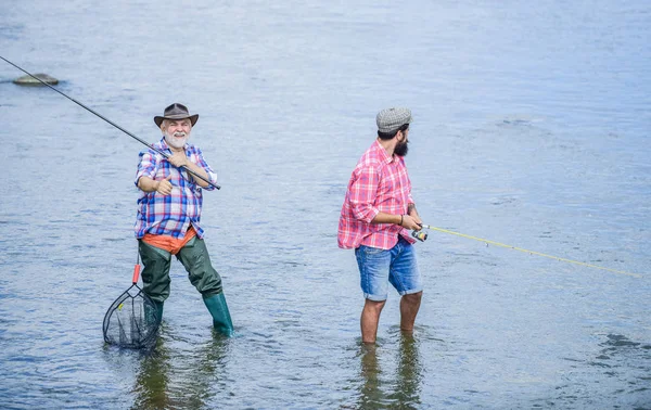 Manlig vänskap. Far och son fiske. Sommar helgen. Fiske tillsammans. Män står i vatten. Fisket är mycket mer än fisk. Lycklig fiskare med fiskespö och nät. Hobby-och sportaktivitet — Stockfoto