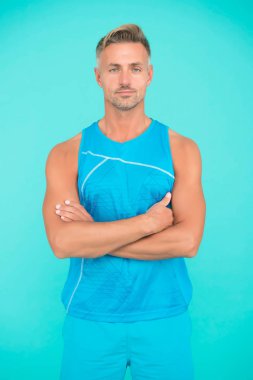 Kaslı vücut. Mavi arka planda bakımlı bir sporcu. Olgun ama hala iyi durumda. Daha sağlıklı olmak için spor yapıyorum. Sağlıklı bir yaşam tarzı. Erkekler için spor kıyafetleri ve spor kıyafetleri. Spor salonundaki adam.