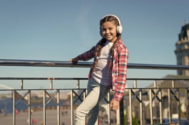 Dinlemeyi hak eden en iyi müzik uygulamaları. Çocuğunuzu en iyi çocuk kulaklıklarıyla mutlu edin. Kız çocuk açık havada modern kulaklıklarla müzik dinler. Her yerde müzik var.