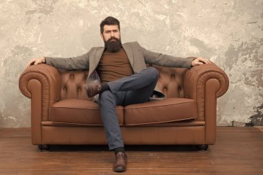 Kendine güvenen yüzü olan sakallı adam deri kanepeye otursun. Loft iç daire. İşadamı emlakçı işi. Mobilya dükkanı. Hipster emlakçı loft tarzı daire. Emlakçı ve kiralama hizmeti. Kiralık daire