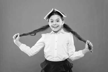 Bırak saçın kendi adına konuşsun. Turuncu arka plan üzerinde uzun esmer saç tutan sevimli küçük kız. At kuyruğu saç giyen baş kitap ile küçük bir okul çocuğu. Okul için saç şekillendirme ve saç bakımı