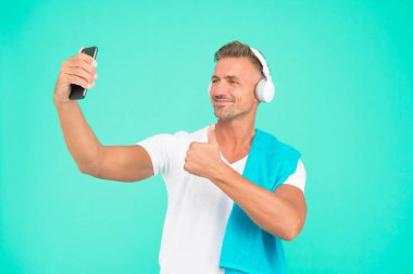 Beden eğitimi konseptinde selfie. Sağlıklı bir yaşam tarzı. Jimnastik estetiği. Olgun ama hala iyi durumda. Daha sağlıklı olmak için spor yapıyorum. Selfie çeken bir sporcu. Sporcu akıllı telefon ve kulaklık