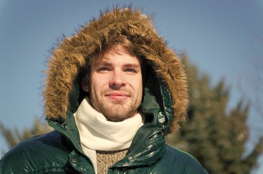 Adam tıraşsız kürk karlı doğa arka plan ile sıcak ceket giymek. Adam tüylü kukuleta ile kış ceket giymek. Hipster kış moda. Hava değişiklikleri için hazır. Kış şık erkek giyim. Kış kıyafeti