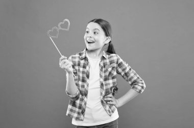 Sevgililer günün kutlu olsun. Küçük çocuk turuncu backgound üzerinde kalp şeklinde parti gözlük ile gülümseyen mutlu. Mutlu küçük kız sopa üzerinde photobooth sahne tutan. Mutlu kutlamazevk