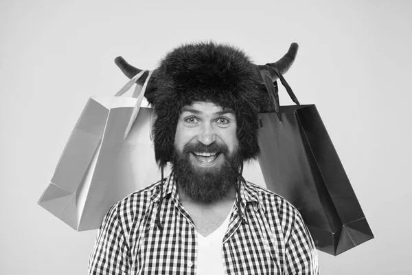 Wild about shopping. Full packages of items. Man strict face wear hat of bull with horns. Hipster shopping addicted or shopaholic. Shopping concept. Guy shopping sales season with discounts