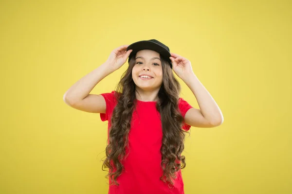 Fashion to say. cool girl with long curly hair. kid fashion. happy girl in trendy hipster cap. hipster child on yellow background. happy childhood. beauty and fashion. small girl with long hair