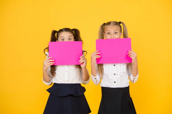 A chamar a atenção. Miúdos felizes com folhas de papel vazias. Miúdos a sorrir com papéis cor-de-rosa. Crianças pequenas sorrindo com cartazes de publicidade em branco. Crianças bonitos publicidade, espaço de cópia — Fotografia de Stock