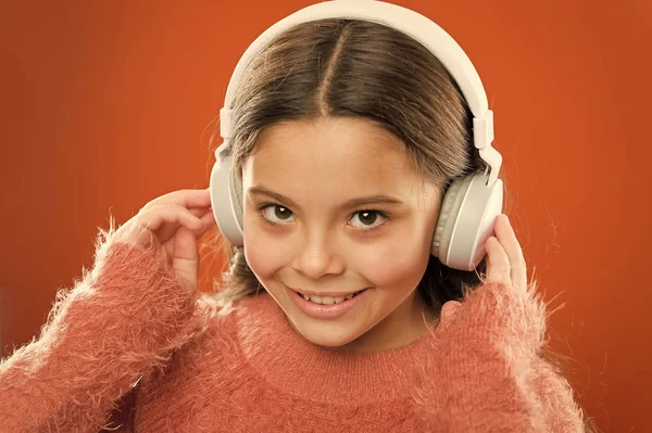 Niña linda niña usar auriculares escuchar música. Niño escuchar música fondo naranja. Música recomendada basada en el interés inicial. Dime lo que escuchas, y te diré quién eres — Foto de Stock
