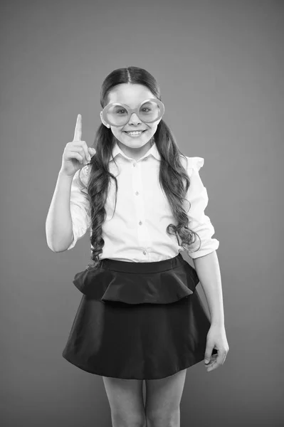 Es una idea graciosa. Niña con gafas graciosas apuntando con el dedo hacia arriba sobre fondo naranja. Niño divertido con gafas de sol con filtro de color. Mis ojos se vuelven graciosos — Foto de Stock