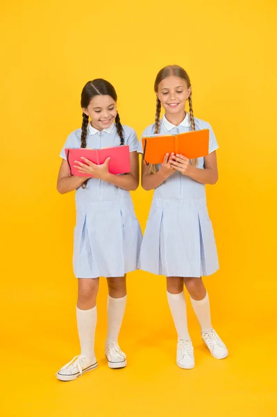 Perdido en un cuento de hadas. de vuelta a la escuela. las niñas pequeñas sostienen el cuaderno de trabajo y el bloc de notas. libro de enciclopedia para niños. las niñas pequeñas aman la literatura. la vieja escuela. amigos felices en uniforme retro. moda vintage niño — Foto de Stock