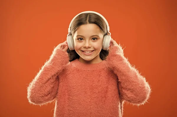 Perfekcyjne słuchawki stereofoniczne. Dziewczyna cute little dziecko nosić słuchawki słuchać muzyki. Dziecko słuchać muzyki pomarańczowe tło. Zalecana muzyka w oparciu o początkowe zainteresowanie. Muzyka daje przyjemność — Zdjęcie stockowe