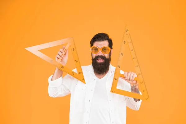 Nerd logró demostrar el teorema. Feliz nerd. Estudia nerd sosteniendo triángulos sobre fondo naranja. Barbudo hombre en gafas nerd de lujo haciendo dibujo técnico — Foto de Stock
