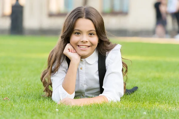 Mental wellness. Little schoolgirl. Relax at school yard. Kid relaxing outdoors. School break for rest. Adorable pupil. Girl kid laying lawn. Girl school uniform enjoy relax. Importance of relaxation — Stock Photo, Image