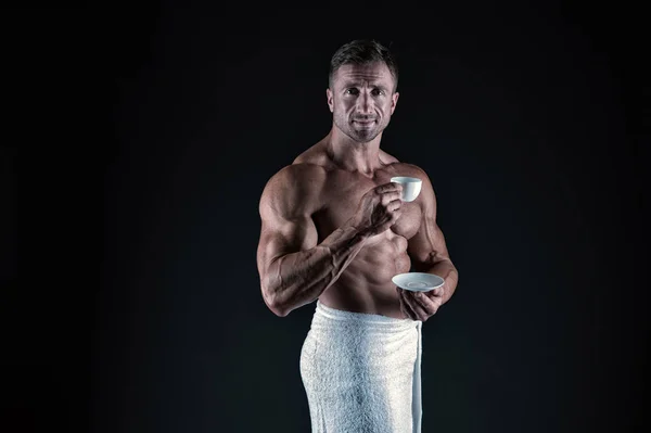 Koffie verbetert de atletische prestaties. Atletische man met fit torso drinken koffie na bad. Sexy bodybuilder Hold koffie kopje op zwarte achtergrond. Zwarte koffie geeft je meer energie, vintage filter — Stockfoto