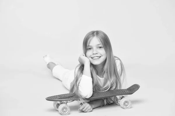 Dítě rozkošné dítě dlouhé vlasy. Šťastné dětství. Jezdím na penci a děláš triky. Holka ráda jezdí na skateboard. Aktivní životní styl. Dívka s penzí na růžovém pozadí — Stock fotografie
