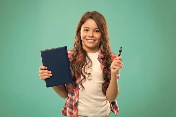 Estoy listo para la escuela. Niño inteligente mantenga pluma y bloc de notas. Chica linda cara feliz le gusta estudiar fondo azul. Niña sostiene libro y pluma. De vuelta al concepto escolar. Proyecto de tarea escolar — Foto de Stock