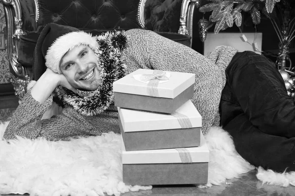 Ambiente navideño. Hombre con sombrero de santa celebrar regalos de Navidad. Hombre feliz con cajas de regalo de Navidad. El tipo está celebrando la Navidad en casa. Entrega regalos de Navidad. Listo para la celebración de Navidad — Foto de Stock