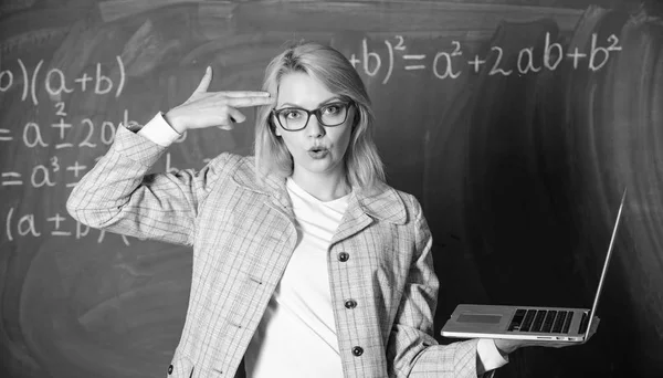 Educator smart clever lady with modern laptop hold gun gesture at her head chalkboard background. Tired teacher annoyed by her job. Educational reforms concept. Woman tired or annoyed holds laptop Stock Picture