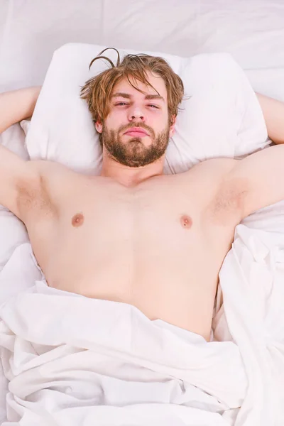 Hombre guapo usando el reloj en la cama después de despertarse por la mañana. Estira después de despertarte por la mañana. Despertando energía . —  Fotos de Stock