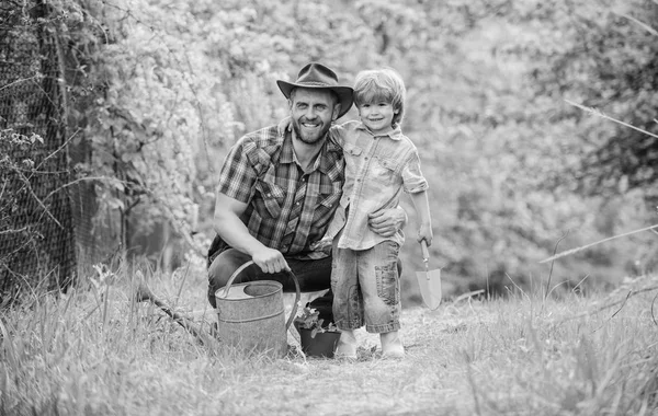 Take care of plants. Boy and father in nature with watering can. Spring garden. Dad teaching little son care plants. Little helper in garden. Planting flowers. Growing plants. Fresh seedlings — Stock Photo, Image