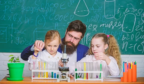 How to interest children study. Explaining biology to children. Fascinating biology lesson. School teacher of biology. Man bearded teacher work with microscope and test tubes in biology classroom
