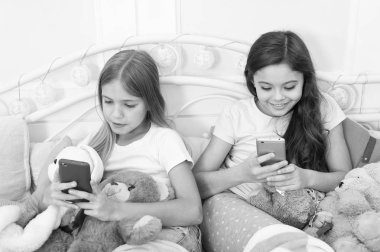 Mutlu Noeller ve mutlu yeni yıl tebrik. Cep telefonu ile mutlu küçük çocuklar. Küçük kızlar yatakta smartphone kullanın. Noel ve yeni yıl hediyesi telefonla sipariş. Modern yaşam