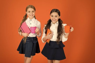 Sakin ol molası. Çay molası sırasında içme. Okul arkadaşları ile içki rahatlatıcı. Öğrenci olmanın tadını çıkarın. Kız çocuklar okul üniforması turuncu arka plan. Kız öğrenci kitap veya Not defteri ve kupa tutun. Okul rutin