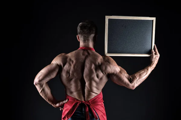 Open hours. Culinary information. Cook hold information board in strong hand back view. Place for information. Advertising information copy space. Muscular man with blank blackboard black background — Stock Photo, Image