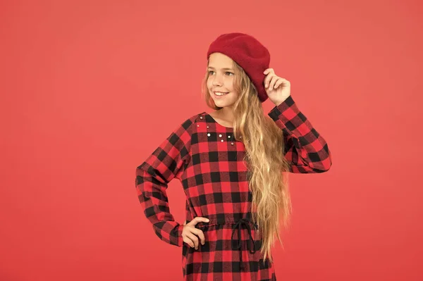 Beret style inspiration. How to wear beret like fashion girl. Kid little cute girl with long hair posing in hat red background. Fashionable beret accessory for female. How to wear french beret